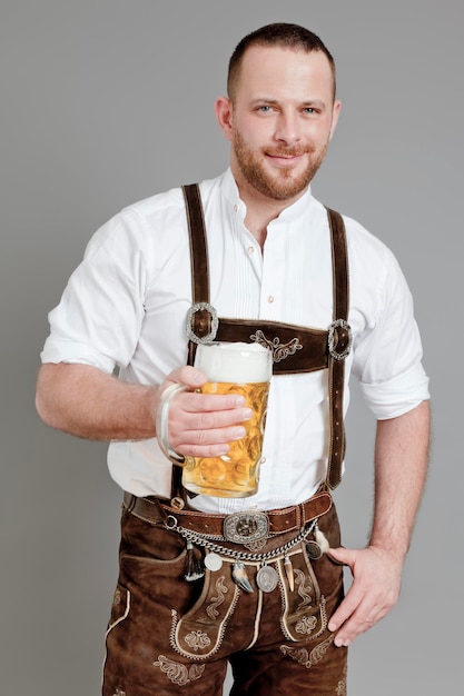Foto portret van een man die een drankje drinkt terwijl hij tegen een grijze achtergrond staat