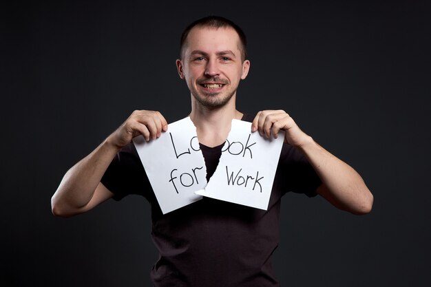 Portret van een man die een inscriptie op papier verscheurt op zoek naar een baan