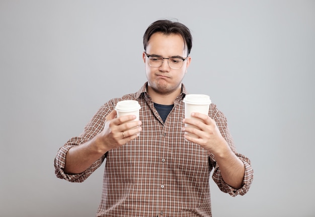 Portret van een man die een kopje koffie kiest geïsoleerd op een grijze achtergrond