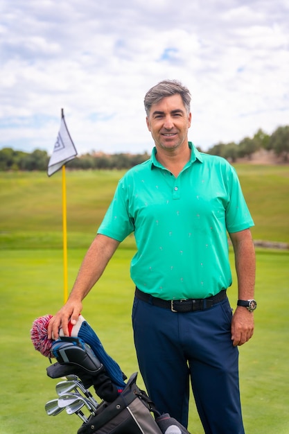 Portret van een man die golf speelt samen met de clubs op de green