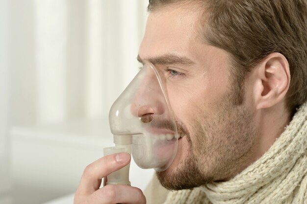 Portret van een man die inademt via een inhalatormasker