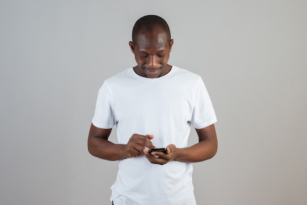 Portret van een man die naar een mobiele telefoon kijkt op een grijze muur
