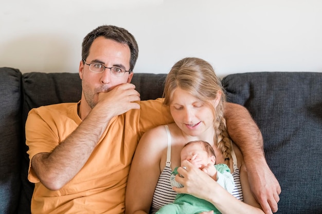 Portret van een man die thuis met een vrouw en een baby op de bank zit