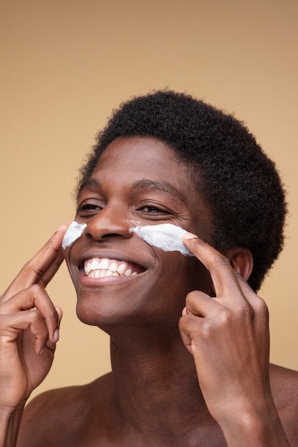 Foto portret van een man die vochtinbrengende crème op zijn gezicht aanbrengt