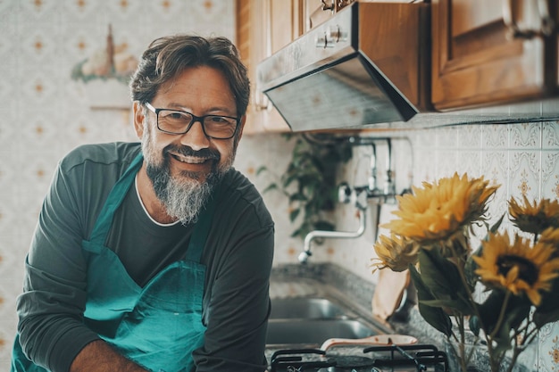 Portret van een man huishoudster die voor de camera kijkt, gelukkig glimlacht en de keuken thuis schoonmaakt Alleenstaande mannelijke mensen levensstijl Huishoudelijk werk persoon Vrolijke man helpt vrouw in huis werk schone baan