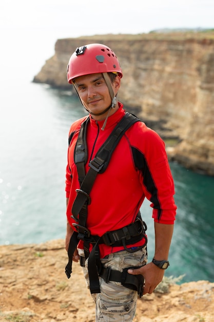 Portret van een man in beschermende kleding en helm aan de rand van een klif Ropejumping