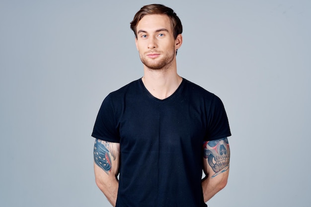 Portret van een man in een blauw t-shirt met een tatoeage op zijn arm blond haar grijze achtergrond foto van hoge kwaliteit