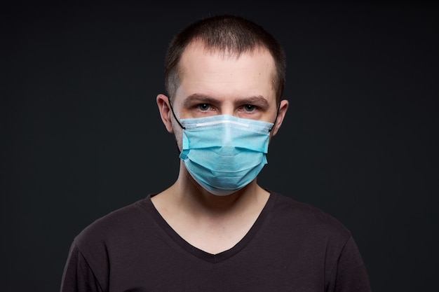 Portret van een man in een medische masker op een donkere muur