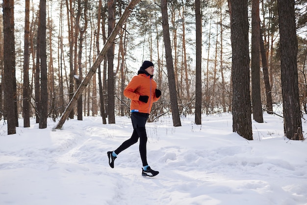 Portret van een man in lichte sportkleding loopt door een winterbos. IJzige dag