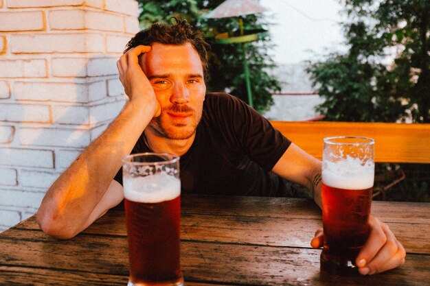 Portret van een man met bier aan tafel bij zonsondergang