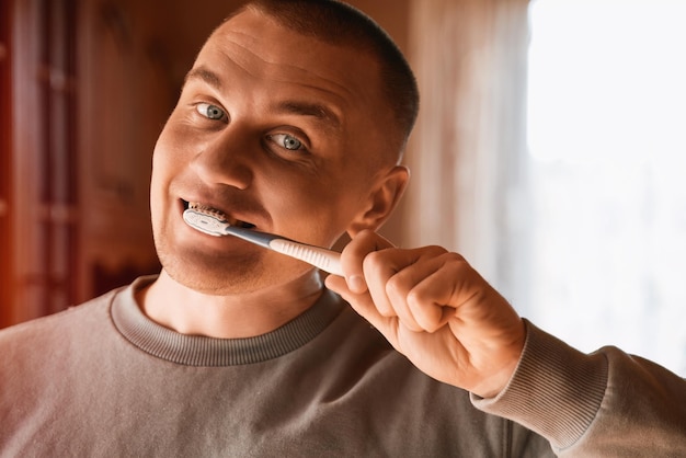Portret van een man met blauwe ogen die tanden poetst
