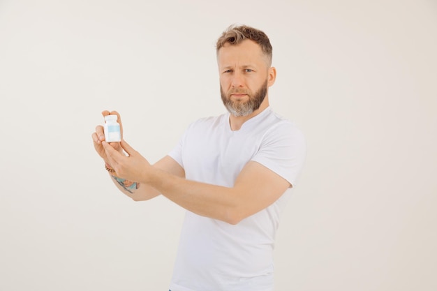 Portret van een man met een baard van middelbare leeftijd met kort haar in een wit t-shirt met een plastic fles erin