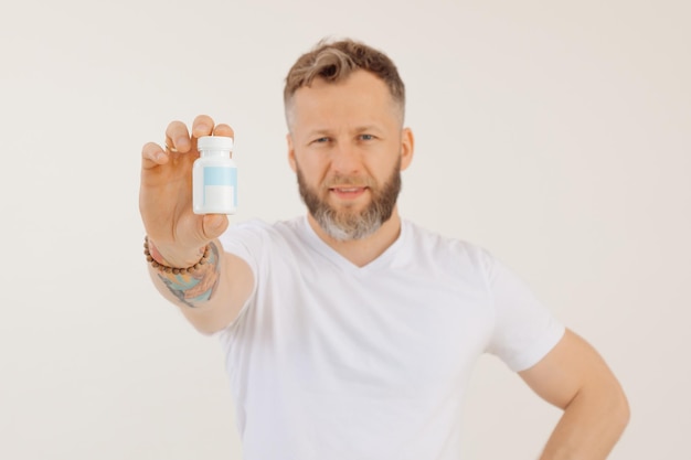 Portret van een man met een baard van middelbare leeftijd met kort haar in een wit t-shirt met een plastic fles erin