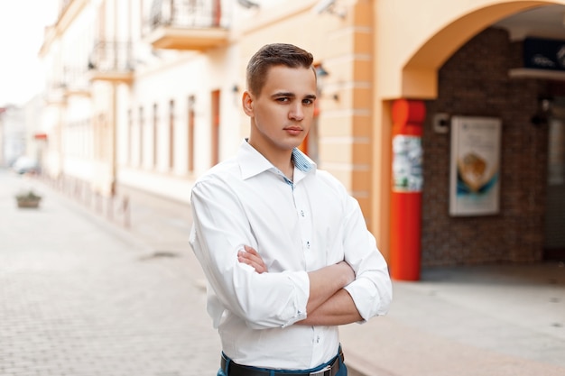 Portret van een man met een gekruiste hand in een wit overhemd op straat