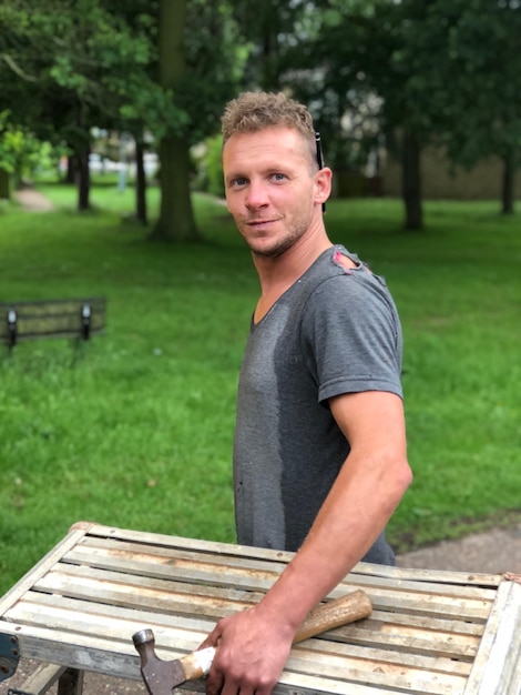 Portret van een man met een hamer op een bankje in het park
