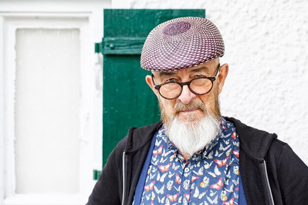 Foto portret van een man met een hoed die tegen de muur staat