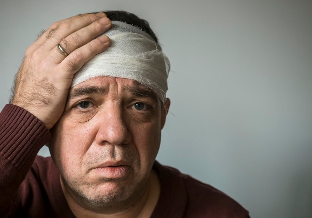 Foto portret van een man met een hoofdwond tegen een grijze achtergrond