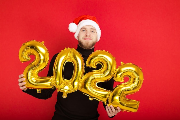 Portret van een man met een kerstmuts en met de nummers 2022 op een rode achtergrond