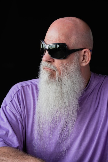 Foto portret van een man met een lange grijze baard in een paarse t-shirt en een zonnebril close-up shot