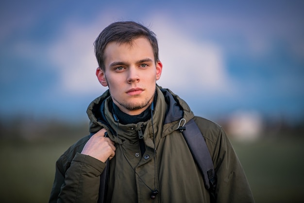 Portret van een man met een rugzak op de natuur tegen de avondlucht