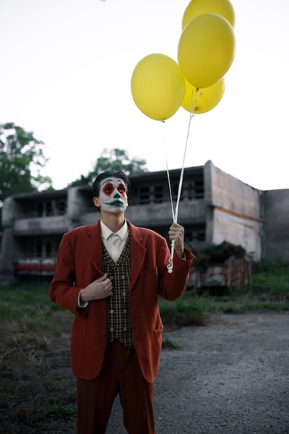 Foto portret van een man met enge clownmake-up en ballonnen