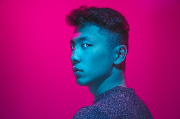 Portret van een man met kleurrijk neonlicht op roze studioachtergrond. Mannelijk model met kalme en serieuze stemming. Gezichtsuitdrukking, cyberpunk, millennials levensstijl en uiterlijk. Toekomst, technologieën.