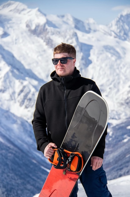 Foto portret van een man met snowboard bovenop een besneeuwde berg.