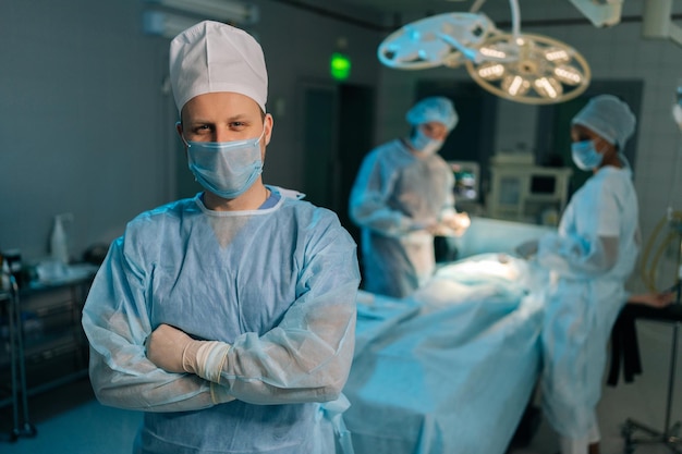 Portret van een mannelijke arts in chirurgische uniformen en maskers die poseert en naar de camera kijkt met