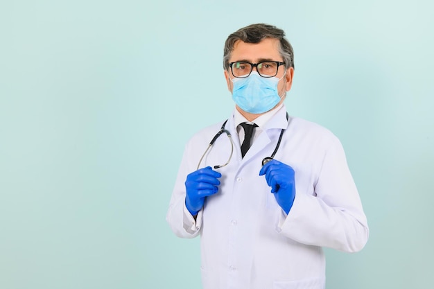 Portret van een mannelijke arts met een masker en handschoenen op een blauwe achtergrond Gezondheidszorgconcept