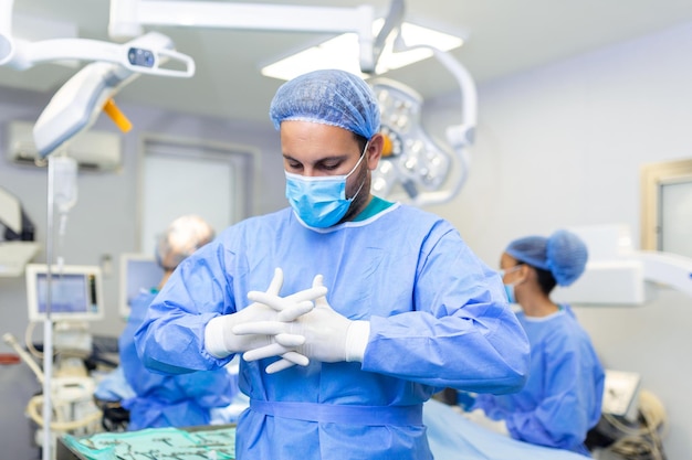 Portret van een mannelijke chirurg met een team artsen op de achtergrond in de operatiekamer