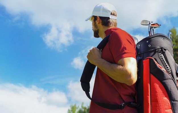 Portret van een mannelijke golfer die een golftas draagt terwijl hij door het groene gras van de golfclub loopt