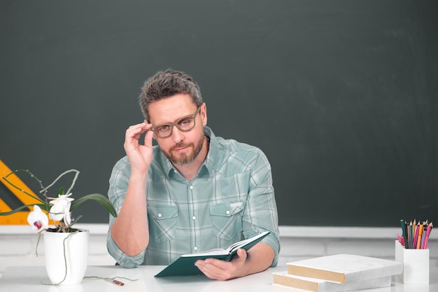 Portret van een mannelijke leraar die lesgeeft aan middelbare scholieren met een computerlaptop in de klas op Blackboard Teachers day