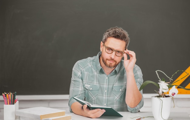 Portret van een mannelijke leraar die lesgeeft aan middelbare scholieren met een computerlaptop in de klas op