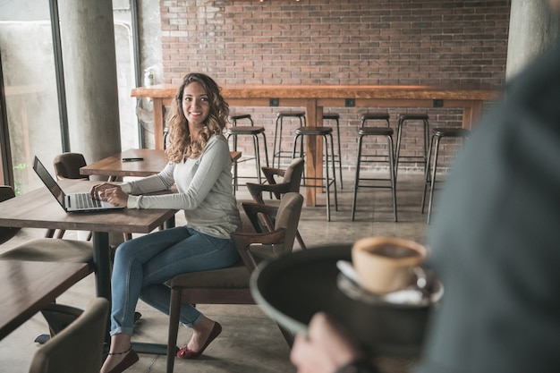 Portret van een mannelijke serveerster die koffie serveert aan een vrouwelijke klant