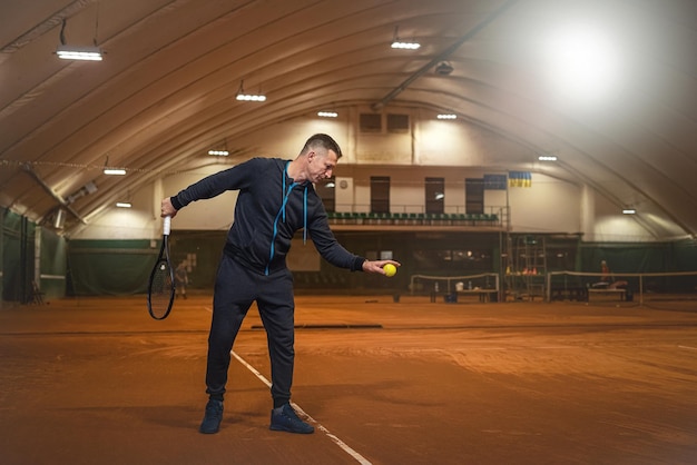 Portret van een mannelijke tennisser die een tennisbal slaat tijdens een training op een uitgegraven baan