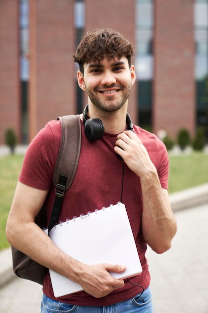 Portret van een mannelijke universiteitsstudent die buiten de universiteitscampus staat
