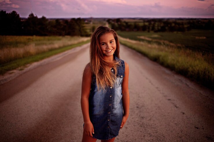 Foto portret van een meisje dat bij zonsondergang op de weg staat