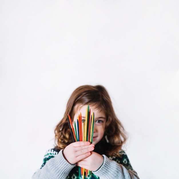 Portret van een meisje dat multi gekleurde plastic stokken houdt