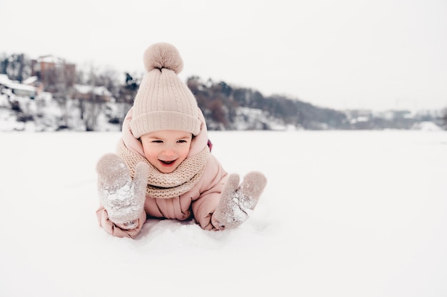 Portret van een meisje dat tijdens een winterwandeling in de sneeuw speelt en sneeuwballen speelt die in de sneeuw rollen en schaatsen