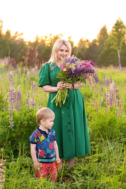 Portret van een meisje en zoon in een bloeiend veld in de zon bij zonsondergang