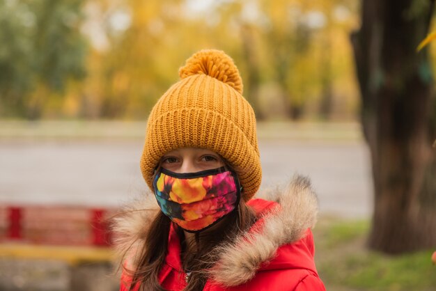 Portret van een meisje in een beschermend masker en een oranje hoed