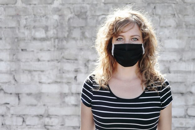 Portret van een meisje in een beschermend masker op een witte bakstenen muur op de achtergrond