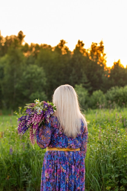 Portret van een meisje in een bloeiend veld in de zon bij zonsondergang