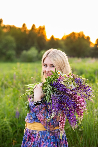 Portret van een meisje in een bloeiend veld in de zon bij zonsondergang