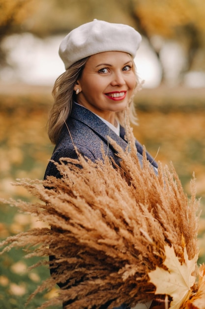 Portret van een meisje in een jasje en birette met een herfstboeket in een herfstpark