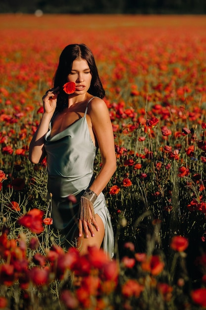 Portret van een meisje in een jurk op een papaverveld bij zonsondergang