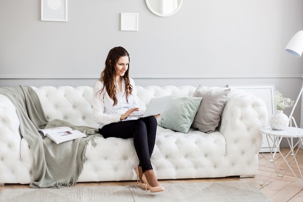 Portret van een meisje in een lichte interieur, een meisje van Europese uitstraling zittend op de Bank, Manager, freelancer