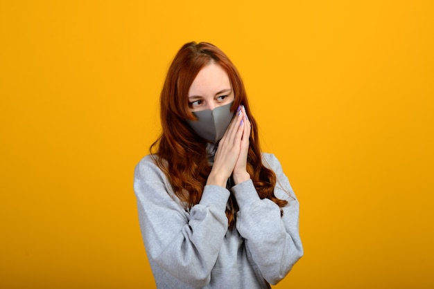 Portret van een meisje in een masker, dat een rubberen handschoen aantrekt. gele achtergrond.