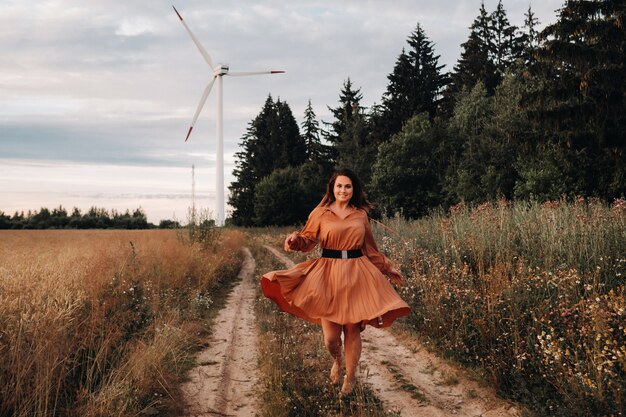 Portret van een meisje in een oranje lange jurk met lang haar in de natuur in de avond