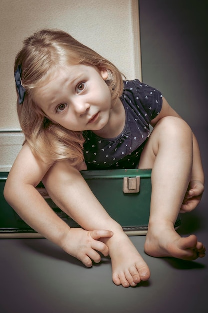 Portret van een meisje in een oude koffer